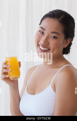 Pretty asian woman holding glass of orange juice Banque D'Images
