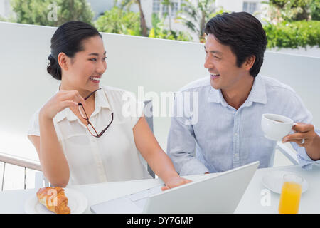 Smiling couple having breakfast together using laptop Banque D'Images