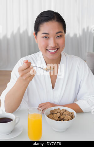 Happy woman in bathrobe avoir son petit-déjeuner Banque D'Images