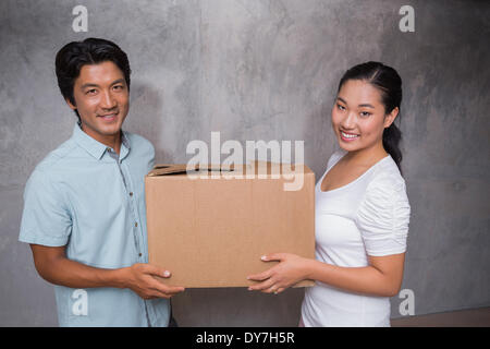 Heureux couple tenant une boîte en carton déménagement Banque D'Images