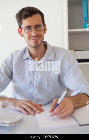 Smiling Casual businessman taking notes à son bureau. Banque D'Images