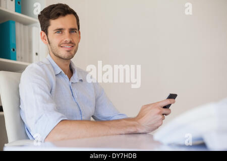 Happy Casual businessman sending a text à son bureau. Banque D'Images