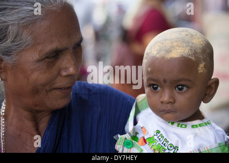 Bébé avec tête couverte de curcuma pendant Chithirai Thiruvizha fête hindoue, Madurai, Inde Banque D'Images