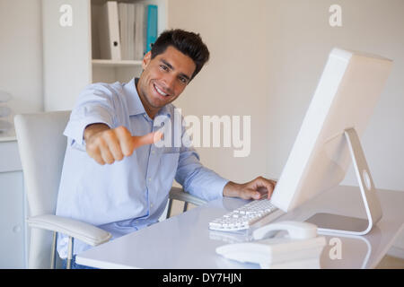 Businessman giving Thumbs up à l'appareil photo à son bureau. Banque D'Images