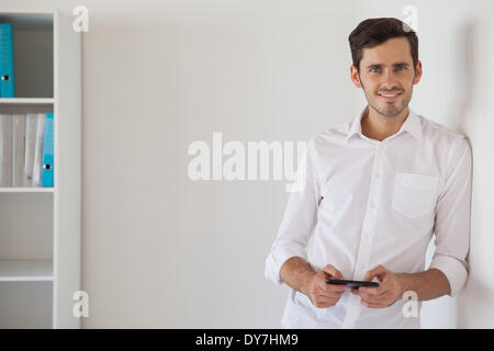 Businessman leaning against wall l'envoi d'un texte Banque D'Images