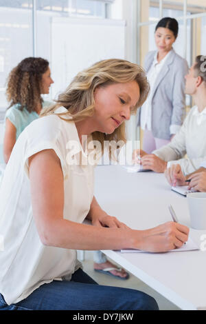 Casual businesswoman taking notes during meeting Banque D'Images