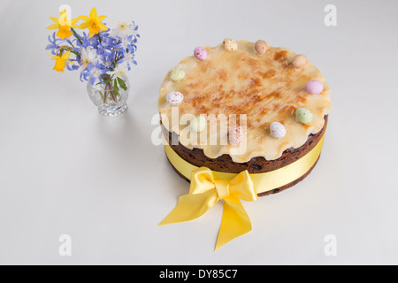 Simnel cake sur un fond clair avec un ruban jaune massepain cannelé avec un arc avec 11 oeufs colorés de fleurs(30) 35 Banque D'Images