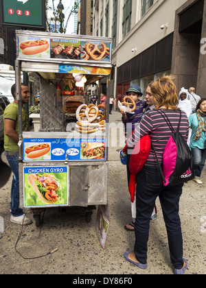 L'achat des bretzels au trottoir hot dog panier vendeur de rue, New York USA Banque D'Images