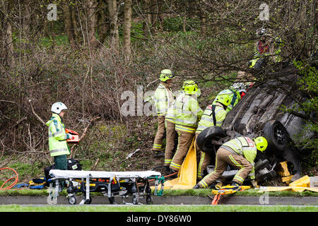 Queenswood dur, Leeds West Yorkshire UK 9 avril 2014. Les services d'urgence assister à un incident survenu à autour de 14 heures dans lequel un véhicule s'est retourné dans une longue rue de banlieue. Deux personnes ont été coupées à l'abri de la voiture qui s'est retrouvée sur son toit dans un bois au bord de la route dans le parc Becketts zone LS6 et retiré de la scène en ambulance. Le West Yorkshire Air Ambulance a également assisté à la scène mais n'a pas été utilisée pour le transport des blessés. Un autre véhicule, une Seat Ibiza jaune, qui a été vu pour être endommagé a également été stationnée à proximité. Crédit : Ian Wray/Alamy Live News Banque D'Images