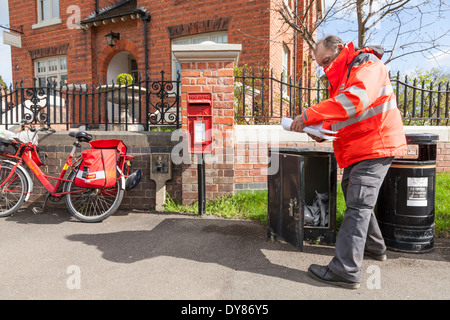 UK facteur sur sa tournée dans une zone rurale, la collecte et la distribution du courrier à partir d'une boîte à l'extérieur de l'ancien bureau de poste, Plumtree, Lancashire, England, UK Banque D'Images
