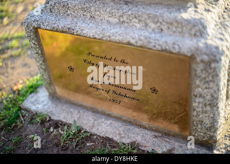 WASHINGTON DC — Une plaque de dédicace en laiton marque la pagode japonaise, un monument en pierre situé parmi les cerisiers du bassin de marée. Cadeau du maire de Yokohama en 1957, la pagode est l'un des nombreux cadeaux diplomatiques historiques du Japon présentés dans la région. Les célèbres cerisiers en fleurs entourant le monument ont été offerts à la ville en 1912. Banque D'Images
