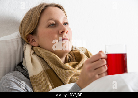 Jeune femme au lit, a un rhume, de boire un thé chaud Banque D'Images