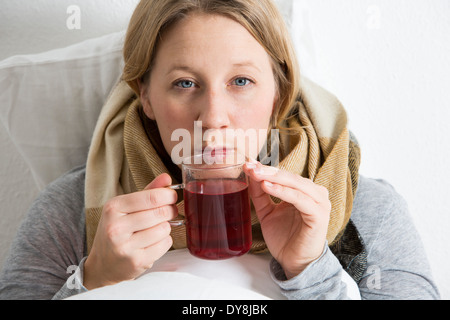 Jeune femme au lit, a un rhume, de boire un thé chaud Banque D'Images