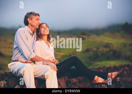 L'amour heureux couple d'âge moyen, moment romantique en admirant le coucher du soleil dans la campagne Banque D'Images