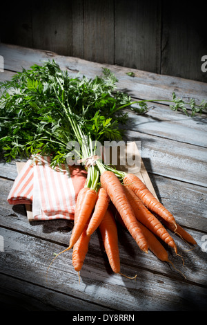 Botte de carottes biologiques sur le chiffon et table en bois gris Banque D'Images