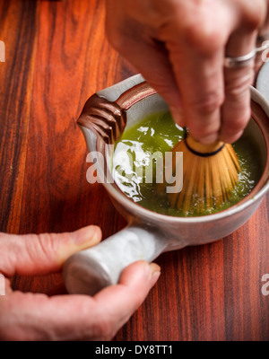 En remuant au fouet avec du thé matcha Banque D'Images