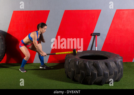 Marteau pneumatique Hits femme entraînement à la salle de sport avec un marteau et le pneu du tracteur Banque D'Images