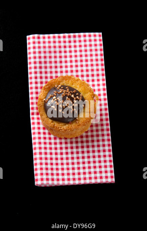 Maison individuelle glacé au chocolat Gâteau éponge sur une serviette en papier à motifs Vichy Banque D'Images