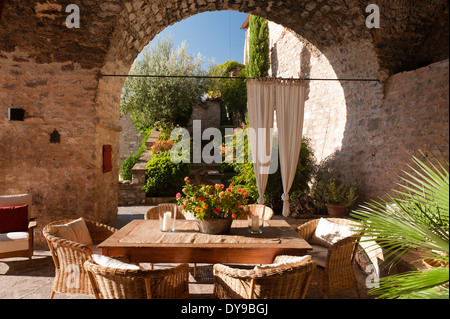 Patio couvert dans une ancienne villa italienne avec table en bois et des chaises en osier. Banque D'Images