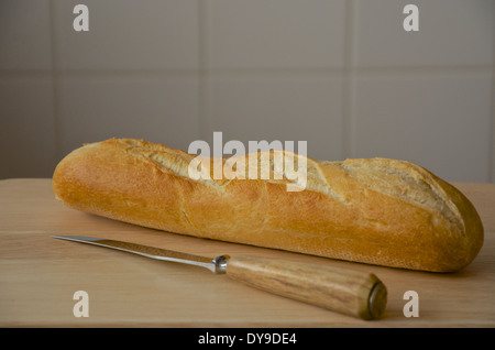 La Baguette et couteau sur une planche en bois avec un sol carrelé background Banque D'Images