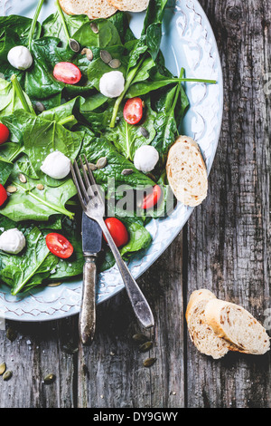 Salade de plaque d'épinards frais, tomates et mozzarella avec du pain. Banque D'Images