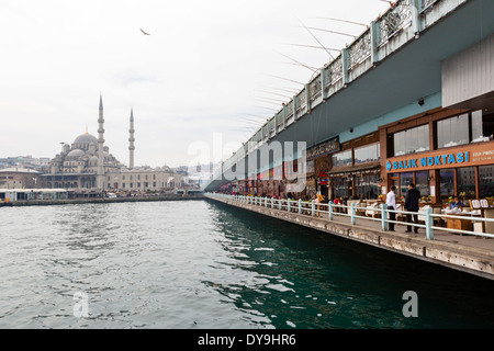 Restaurants de poissons sous le pont de Galata sur la Corne d'or avec la nouvelle mosquée (Yeni Camii) derrière, district d'Eminonu, Istanbul, Turquie Banque D'Images