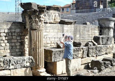 L'homme d'âge moyen de prendre une photo de l'ancienne colonnes de pierres dans le théâtre romain d'Arles, France. Banque D'Images