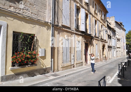 Femme de prendre une photo de la fenêtre provençale et des fleurs dans la rue vide Arles France Banque D'Images