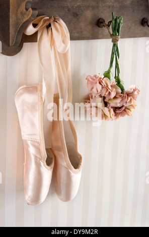 Paire de chaussures de ballet pointe suspendu à un rack sur fond à rayures vintage pour copy space Banque D'Images