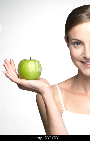 Young woman holding up green apple Banque D'Images