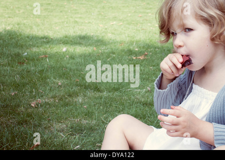 Little girl eating snack sucré à l'extérieur Banque D'Images