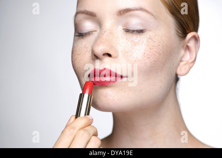 Young woman putting on lipstick Banque D'Images