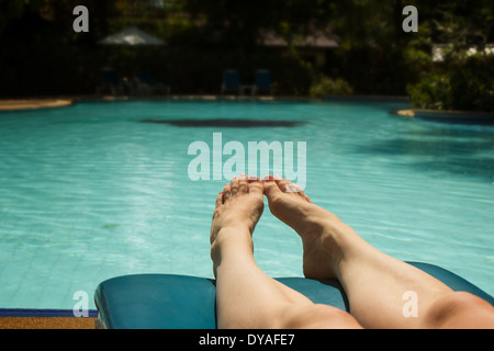 Libre de pieds d'une femme soleil transats à côté d'une piscine Banque D'Images