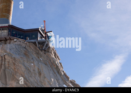 Un touriste se trouve dans le 'Step dans le Vide' boîte de verre sur l'Aiguille du Midi (3842 m) sommet de montagne au-dessus de Chamonix Mont-Blanc Banque D'Images