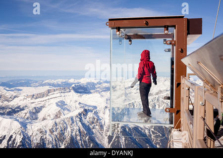 Un touriste se trouve dans le 'Step dans le Vide' boîte de verre sur l'Aiguille du Midi (3842 m) sommet de montagne au-dessus de Chamonix Mont-Blanc Banque D'Images