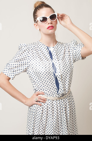 Femme avec bun hairstyle portant des lunettes de soleil œil de chat,Caucasian woman, femme model posing in studio contre fond gris clair Banque D'Images