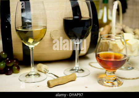 Vin rouge et blanc dans les verres, l'eau de vie. Sur le fond du baril et wine corks panier, bol de fromage et une bouteille Banque D'Images