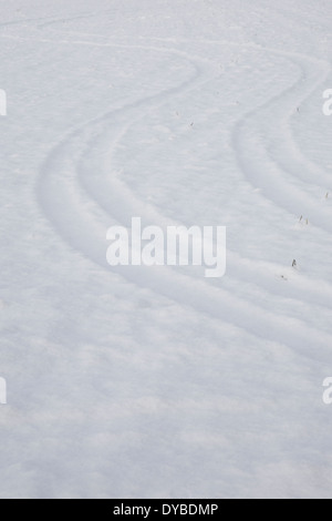 Scène de la neige d'hiver dans le sud de l'Angleterre, montrant les traces de pneus ondulées dans un champ neigeux profonds Banque D'Images