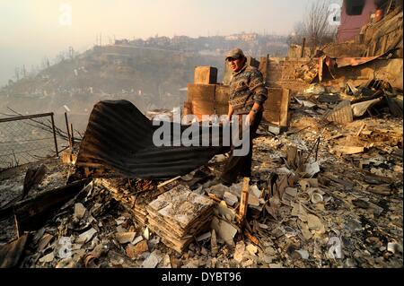 Valparaiso. 13 avr, 2014. Un résident se penche sur une maison distroyed par un incendie à Valparaiso, Chili le 13 avril 2014. Au moins 11 personnes ont été tuées au cours du week-end dans un énorme feu de forêt qui a éclaté dans le port de la ville de Valparaiso, les autorités ont déclaré dimanche. La présidente Michelle Bachelet a déclaré l'état d'urgence dans la ville et a envoyé l'armée dans le maintien de l'ordre comme des milliers de résidents ont été évacués. © Pablo Ovalle/AGENCIA UNO/Xinhua/Alamy Live News Banque D'Images