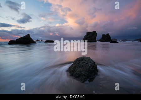 Des flaques, une vague, et la mer, des rochers, des piles au coucher du soleil le long de la plage de Bandon, Oregon. L'hiver. USA Banque D'Images