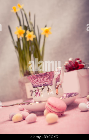 L'installation de pâques avec une tasse, narcisses et sucreries Banque D'Images