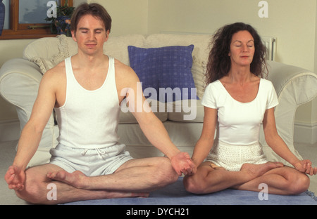 Couple faisant du yoga à la maison assis en position du lotus Banque D'Images