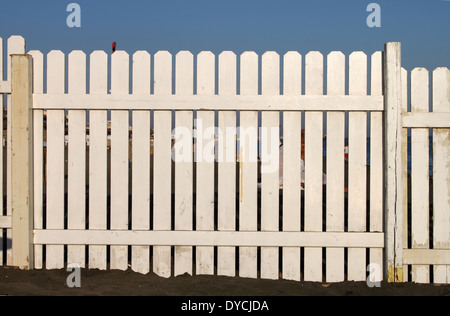 Une clôture blanche en bois sur la plage sur un fond de ciel bleu Banque D'Images