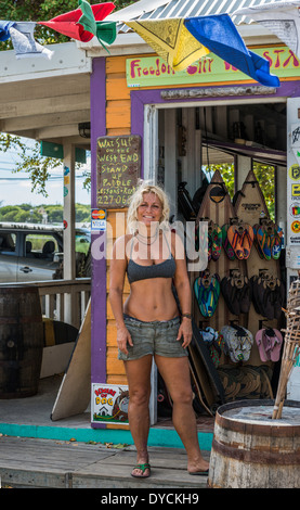 Un Blanc, blond femme propriétaire d'un paddle board entreprise en dehors de sa boutique à Saint Croix, Îles Vierges des États-Unis. Banque D'Images