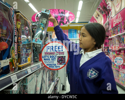 Jeune Thaïlandaise / French Girl sélectionne un 'Monster' Haut de poupée les étagères dans un jouet superstore Banque D'Images