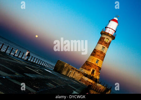 Roker, UK. 14 avril, 2014. La pleine lune se lève sur Roker, Sunderland. Roker Phare a été récemment restauré dans la première phase de £1.35m programme de restauration pour les 110 ans de la jetée Roker énumérés par Sunderland City Council. Crédit : Paul Swinney/Alamy Live News Banque D'Images