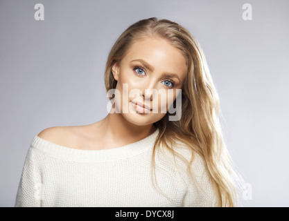 Portrait d'une belle jeune femme blonde à l'arrière-plan gris. Modèle a de longs cheveux blonds, yeux bleus et belle peau propre Banque D'Images