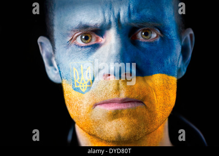 Un regard intense d'un homme avec le visage peint avec pavillon ukrainien. Banque D'Images