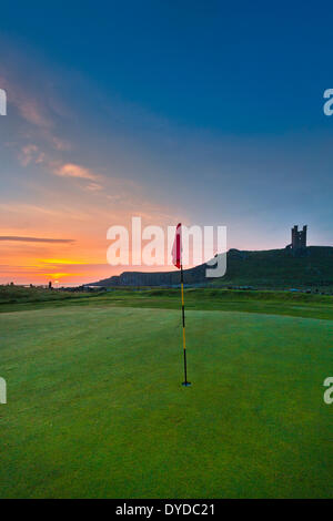 Château de Dunstanburgh dans Northumberland derrière un livre vert sur le parcours de golf local. Banque D'Images