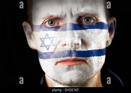 Un regard intense d'un homme avec le visage peint avec le drapeau d'Israël. Banque D'Images